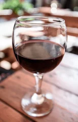 Fotobehang A glass of red wine on the vibrant restaurant background. Selective focus. © vladhhe