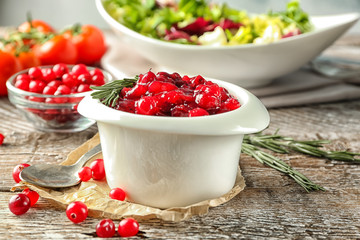 Delicious cranberry sauce in bowl on wooden background, close up