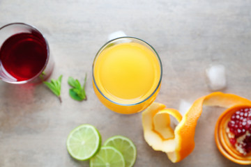 Glasses of Tequila Sunrise cocktail and ingredients on grey background