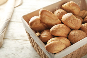 Wicker basket with different types of fresh bread on table