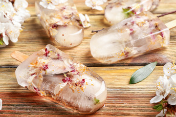 Homemade ice pops with flowers on wooden background