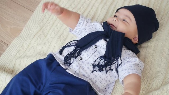 Pretty baby boy is lying on the white carpet
