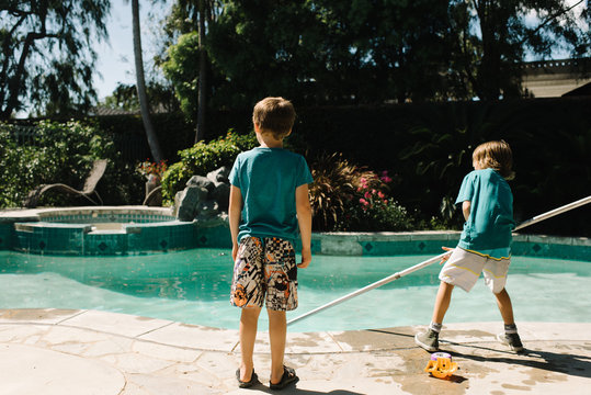 Two boys cleaning swimming pool