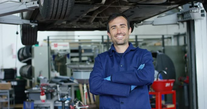 Portrait of a young beautiful car mechanic in a car workshop, in the background of service. Concept: repair of machines, fault diagnosis, repair specialist, technical maintenance and on-board computer