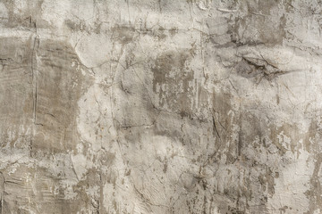 Texture of an embossed antique concrete wall with cracks and a ruined plaster protective layer, abstract background