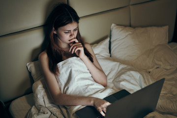 pensive woman behind laptop in bed