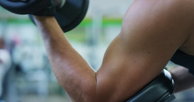 Guy bodybuilder in the gym, works with a barbell, bench press, improving triceps, large pectorals muscle, anterior deltoids muscle Concept love sports, go to the gym, eat right, slim body, be healthy.