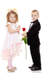 The boy gives the girl a flower.