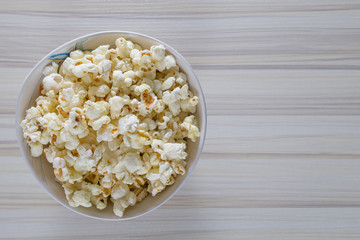 Popcorn in white bowl closeup on wood table