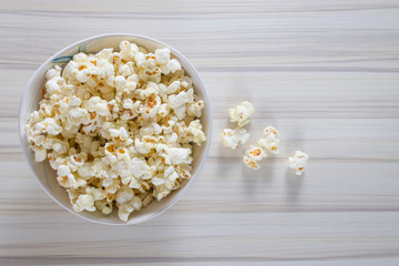 Popcorn in white bowl closeup on wood table