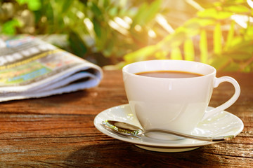 coffee cup clock and news paper on old wooden table