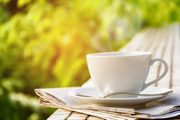 coffee cup clock and news paper on old wooden table