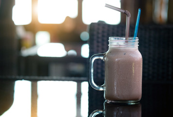 Chocolate smoothie on the table, coffee shop background, warm and dark tone sunbeam filtered process, selective focus.