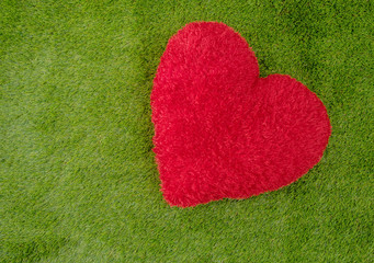 Red heart on green grass for love background concept