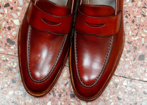 Pair of leather cherry calf penny loafer shoes on the stone floor together one by one closely. Close up