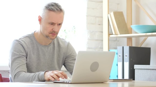Middle Aged Man Working On Laptop in Office