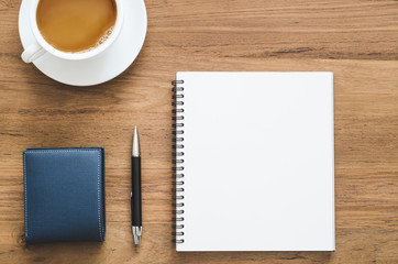 wooden desk table with blank notebook, pen, wallet and cup of coffee.