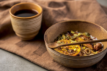 porridge with fried banana and orange. Bowl of oatmeal porridge with banana, Cinnamon. Hot and healthy food for Breakfast, with toast and coffee, on a wood round table with a butter knife.