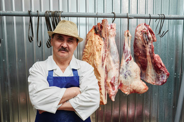 Portrait kazakh butcher at work, cuts meat