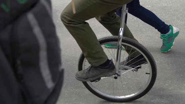 Closeup of a man's feet that rides on a unicycle. Close-up of a bicycle wheel. Good skill. Bad ride. He turns the pedals.