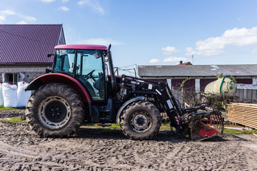 Agricultural machineryand equipment. Tractor with front loader for manure. The yard of a dairy farm. Podlaskie, Poland.