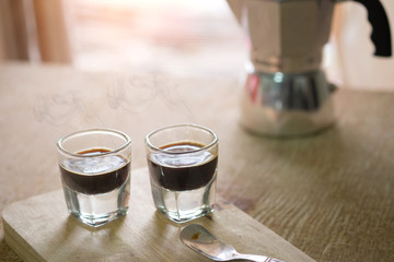 two espresso cup on the wood table with morning vintage tone, espresso coffee pot in blur background.