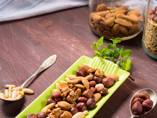 Nut mix on green dish - walnuts, pine nuts, peanuts, hazelnuts
