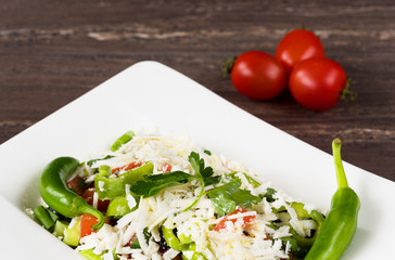 Traditional classic Shopska salad with tomatoes, peppers, cucumbers and cheese in white dish on grey wooden table. Bulgarian cuisine, Balkan culture