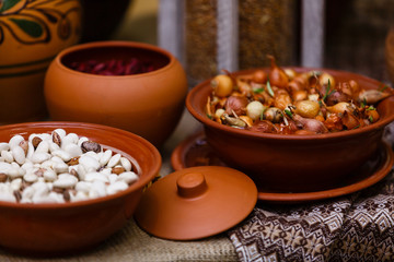 Colorful beans seeds in a clay ethnic painted plate on a dark background. Horizontal placement.