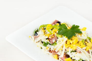 Traditional Bulgarian Shepherd salad with tomatoes, peppers, cucumbers, mushrooms, ham, cheese and eggs in white dish on white wooden table. Bulgarian cuisine, Balkan culture