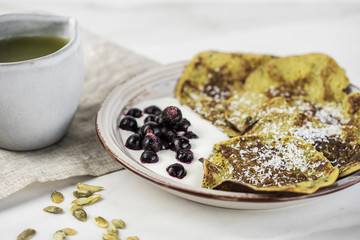 Green pancakes with spinach and bananas decorated citrus, mint and cranberry