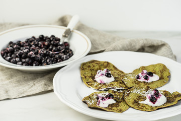 Green pancakes with spinach and bananas decorated citrus, mint and cranberry.photo on phone