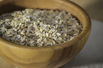 Oat flakes in a wooden plate close-up