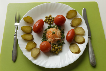Spicy pickled cucumbers and tomatoes, cabbage with carrots,  green peas on a white dish on white background