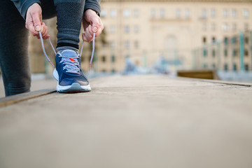 Female runner tying shoe lace in a urban area.