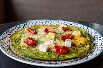 Spinach omelette with tomatoes and cheese on top