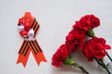Carnation flowers and George Ribbon on abstract light background. Victory Day - May 9. Jubilee 70...