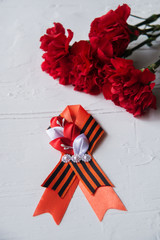 Carnation flowers and George Ribbon on abstract light background. Victory Day - May 9. Jubilee 70...