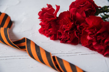 Carnation flowers and George Ribbon on abstract light background. Victory Day - May 9. Jubilee 70...