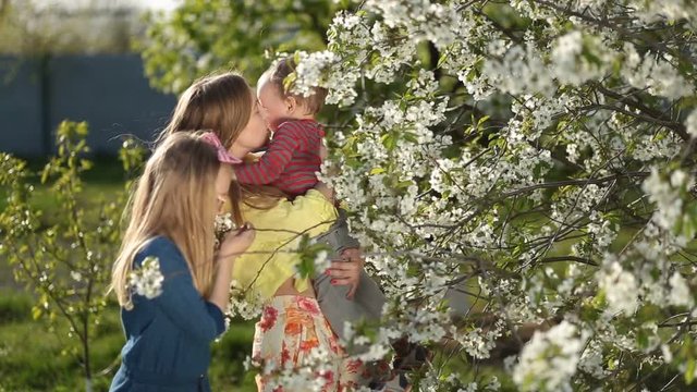Mother with kids smelling blooming cherry tree