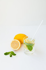 Homemade lemonade with water, lemon and mint leaves in a glass on a white background.