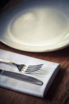 Fork and knife on a table, near a plate