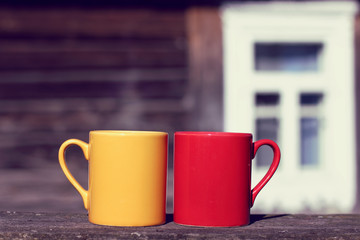  coffee pause in the fresh air/ Two mugs stand on a table on the background of an old wooden house in the street in the afternoon