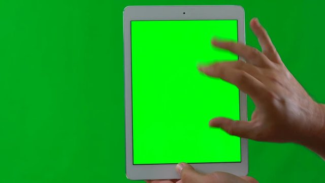 Man using tablet device against green screen.