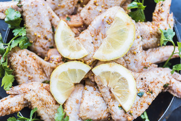 Fototapeta na wymiar Fresh chicken wings, lemon, parsley on a baking sheet closeup