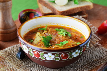 Simple sauerkraut soup with vegetables in a traditional bowl on a wooden background. Fastening food. Vegetarian food. Healthy food concept