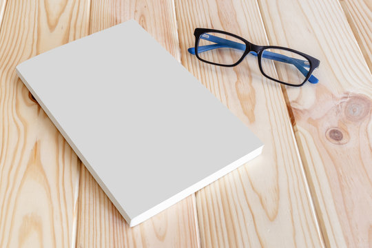 Book and glasses mockup on wooden background.