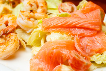 Background from salad of romaine lettuce with prawns, smocked salmon, croutons, grilled chicken, cherry tomatoes with caesar dressing and grated parmesan