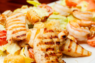 Background from salad of romaine lettuce with prawns, smocked salmon, croutons, grilled chicken, cherry tomatoes with caesar dressing and grated parmesan