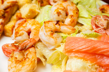 Background from salad of romaine lettuce with prawns, smocked salmon, croutons, grilled chicken, cherry tomatoes with caesar dressing and grated parmesan